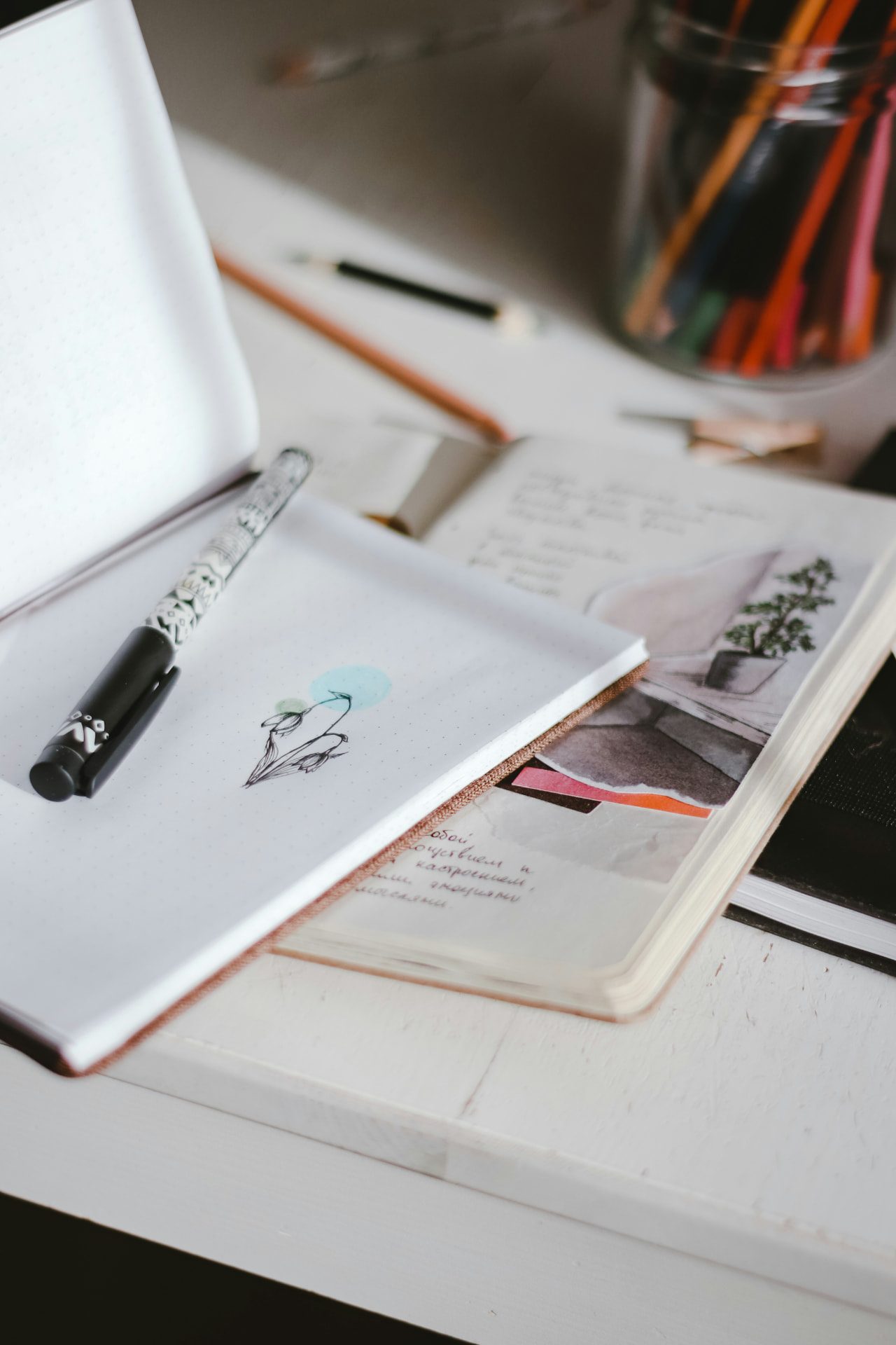 Offenes Notizbuch mit handschriftlichen Notizen und Stiften
